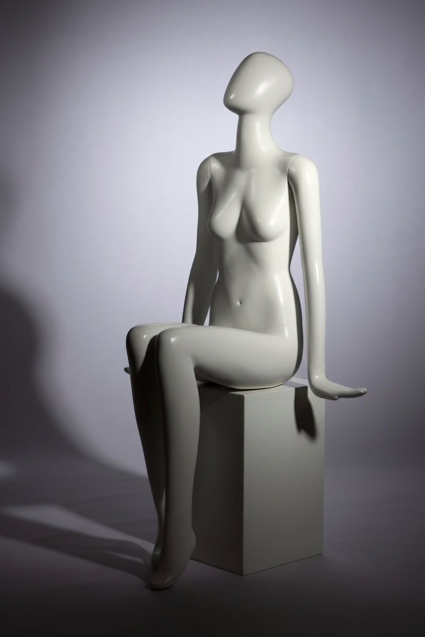 Faceless female mannequin. White, matte with faceless head. Glove hands. Seated